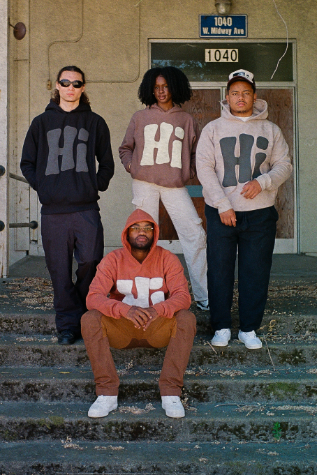 A group of four people dressed in hoodies, standing together and smiling for a picture.